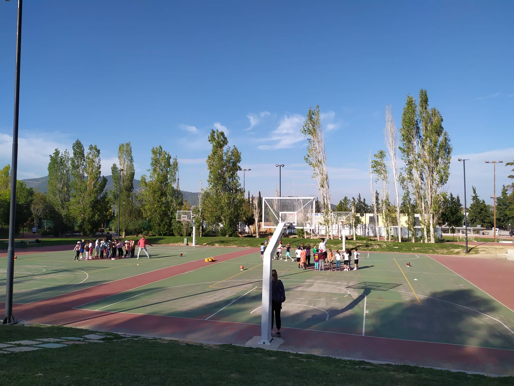 Φωτογραφία του γηπέδου μπάσκετ, όπου τα παιδιά έχουν χωριστεί σε δύο ομάδες.